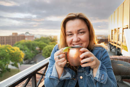 a single woman in her 40s wearing a denim jean jacket enjoying a mule cocktailの写真素材