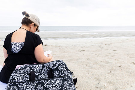 a woman sitting on the beach alone reading a book