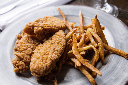 A plate of chicken tenders and thin skinny golden french fries
