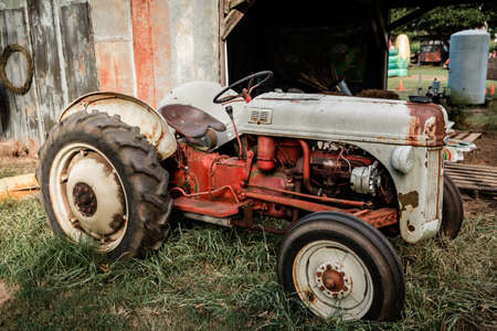 a vintage old antique res and gray tractor at a rural farmの写真素材