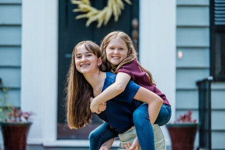 A father holding his 10 year old daughter piggyback on his back while outsideの写真素材