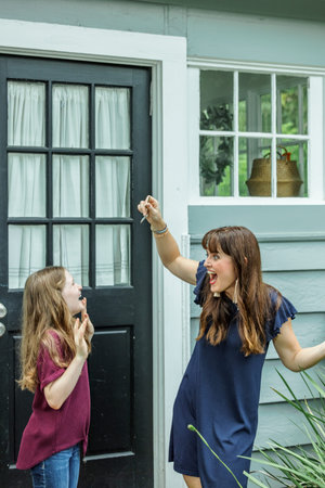 A woman holding up the house key to her daughter for their new home in this fast paced real estate marketの写真素材