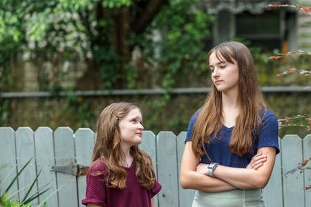 Two sisters and one is a teenager not happy with her little sisterの写真素材