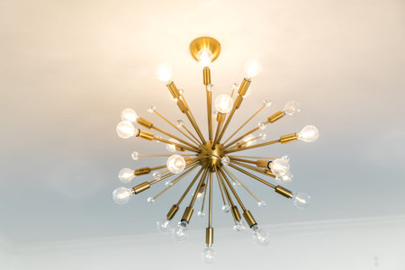 Retro starburst warm gold lighting fixture against a white wall