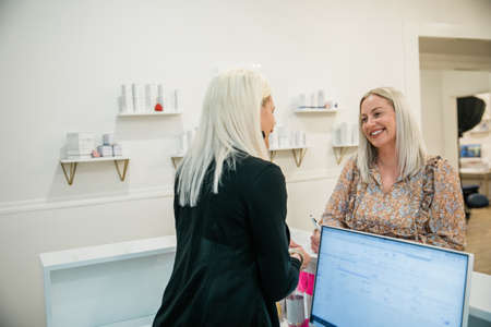 A small business owner checking in a guest client at a wellness spaの写真素材