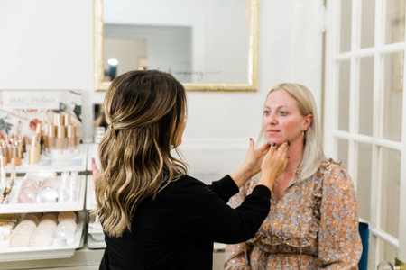 Cosmetologist applying foundation makeup to a blond woman in a makeup chair