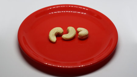 three cashew nuts is on a white background on a red plate