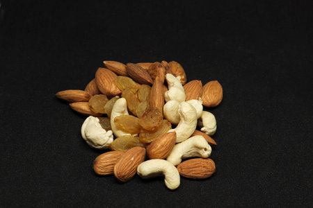 The healthy dry fruit, almond, cashews, and grapes. On a black background