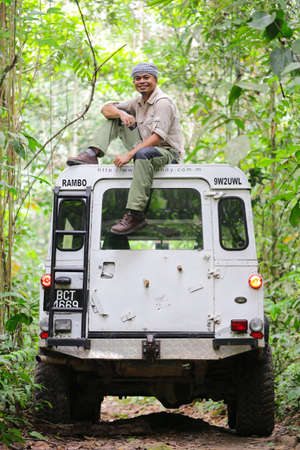 Kuala Tahan, Pahang, Malaysia - July 6 2017 : a man are standing on the roof of old 4x4 off-road vehicle, enjoying the view of Rainforestのeditorial素材
