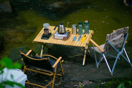 Outdoor kitchen equipment and wooden table set in camping area at natural parklandの写真素材