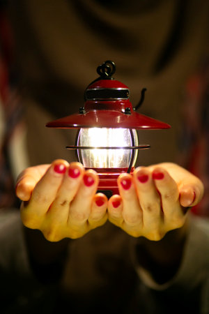 Female camper holding a Camping lantern in the dark forest.の写真素材