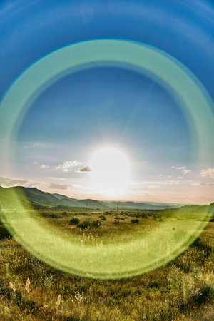 Halo effect around the sun with round rays - beautiful landscape of steppe and stone mountains along the road from the city of Ust-Kamenogorsk to the Sibiny lakes (Sibinskiye Ozora), East Kazakhstanの写真素材