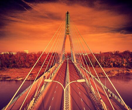 Beautiful panoramic aerial drone view to Swietokrzyski Bridge (English: Holy Cross Bridge) - is a cable-stayed bridge over the Vistula river in Warsaw, Poland in autumn November evening at sunsetの写真素材