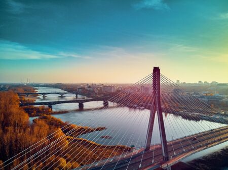 Beautiful panoramic aerial dsrone view to Swietokrzyski Bridge (Polish: Swietokrzyski) and The PGE Narodowy or National Stadium - football stadium located in Warsaw, Poland in autumn evening at sunsetの素材 [FY310134802502]