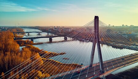 Beautiful panoramic aerial dsrone view to Swietokrzyski Bridge (Polish: Swietokrzyski) and The PGE Narodowy or National Stadium - football stadium located in Warsaw, Poland in autumn evening at sunsetの写真素材