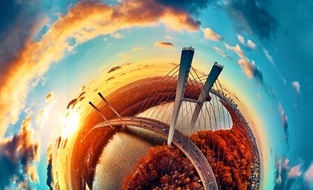 Beautiful panoramic aerial drone view to cable-stayed Siekierkowski Bridge over the Vistula river and Warsaw City skyscrapers, Poland in gold red autumn colors in November evening at sunsetの写真素材