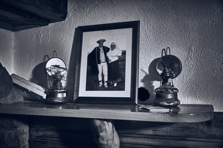 An old family photo of the housekeepers stands in a frame on the fireplace next to the kerosene lamp