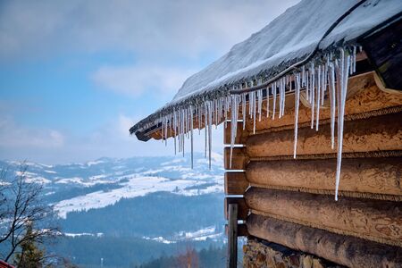 Strong real winter in the south of Poland - huge icicles hanging from the roof against the blue sunny skyの写真素材