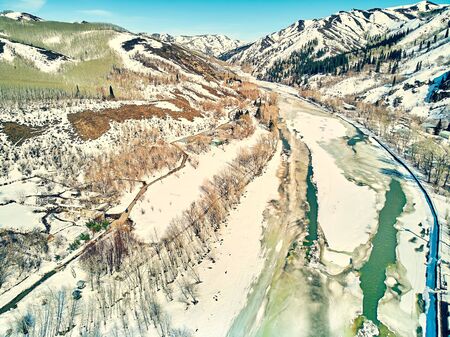 Panoramic aerial view: beautiful spring landscape: the Ulba river in Kazakhstan wakes up from winter sleep - ice drift - snow and ice are melting in the mountains, the bright sun is shining, Qazaqstanの写真素材