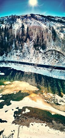 Panoramic aerial view: beautiful spring landscape: the Ulba river in Kazakhstan wakes up from winter sleep - ice drift - snow and ice are melting in the mountains, the bright sun is shining, Qazaqstanの写真素材