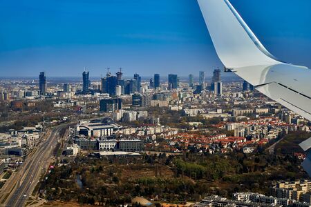 Beautiful panoramic aerial cityscape - view from the window of the plane landing at the center of Warsaw (Poland) with skyscrapers, with parks and residential areas, early spring at sunsetの写真素材