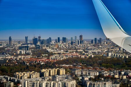 Beautiful panoramic aerial cityscape - view from the window of the plane landing at the center of Warsaw (Poland) with skyscrapers, with parks and residential areas, early spring at sunsetの写真素材