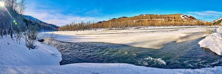 Panoramic aerial view: beautiful spring landscape: the Ulba river in Kazakhstan wakes up from winter sleep - ice drift - snow and ice are melting in the mountains, the bright sun is shining, Qazaqstanの写真素材