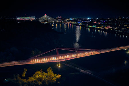 Beautiful panoramic aerial drone night sunset view to the new pedestrian and bicycle bridge connecting the banks of the Vistula, Warsaw, Poland, EU.の写真素材