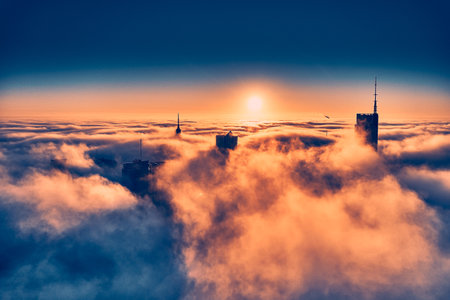 Beautiful panoramic aerial drone view of skyscrapers sticking out of low fog at sunrise, Warsaw, Poland, EU.の写真素材