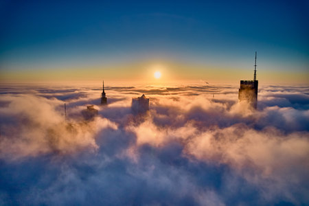 Panoramic aerial drone view of skyscrapers sticking out of low fog at sunrise, Warsaw, Poland, EU.の写真素材