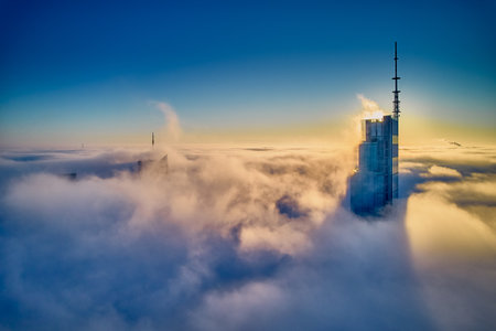 Beautiful panoramic aerial drone view of skyscrapers sticking out of low fog at sunrise, Warsaw, Poland, EU.の写真素材