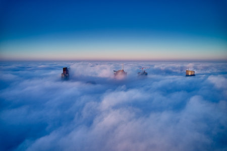 Panoramic aerial drone view of skyscrapers sticking out of low fog at sunrise, Warsaw, Poland.の写真素材