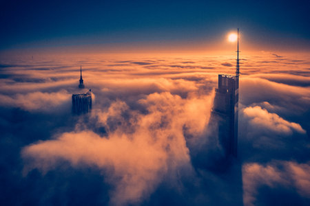 Beautiful panoramic aerial drone view of skyscrapers sticking out of low fog at sunrise, Warsaw, Poland, EU.の写真素材