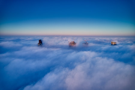 Beautiful panoramic aerial drone view of skyscrapers sticking out of low fog at sunrise, Warsaw, Poland, EU.の写真素材