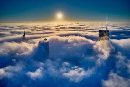 Beautiful panoramic aerial drone view of skyscrapers sticking out of low fog at sunrise, Warsaw, Poland, EU.の写真素材