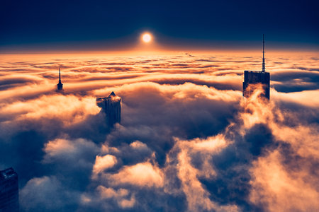 Panoramic aerial drone view of skyscrapers sticking out of low fog at sunrise, Warsaw, Poland, EU.の写真素材