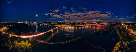 Beautiful panoramic aerial drone night sunset view to the new pedestrian and bicycle bridge connecting the banks of the Vistula, Warsaw, Poland, EU.の写真素材