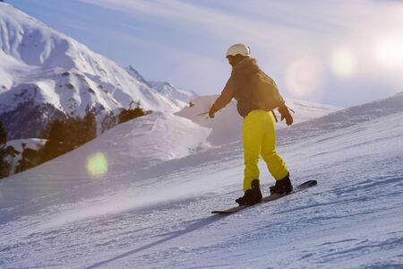 Sporty female snowboarder riding the slopeの写真素材