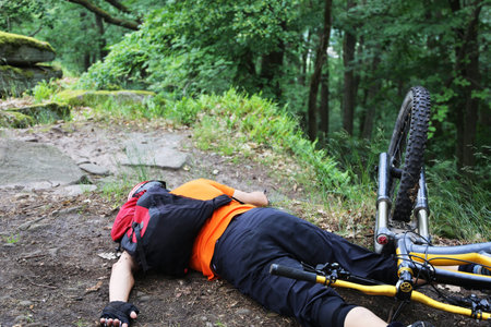 Accidental mountain biker lies injured on the ground (model released)