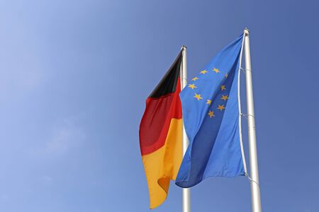 German and european flag in front of a blue skyの写真素材