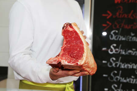 Butcher holds Dry Aged T-Bone Steak in handの写真素材