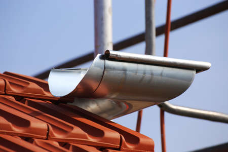 Close-up of a newly installed gutter in the course of plumbing work during roofingの写真素材