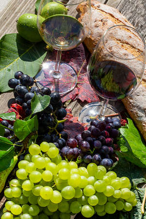 Symbol image of the grape harvest: Ripe grapes decorated with wine glasses on a wooden tableの写真素材
