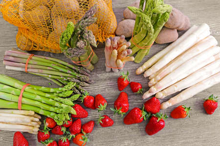 Green asparagus, white asparagus and fresh strawberries decorated on a rustic wooden tableの写真素材