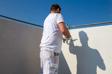 Plasterer plasters the facade of a new buildingの写真素材