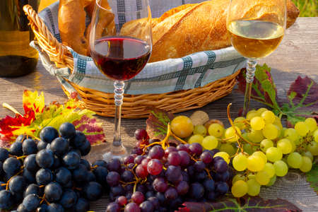 Symbol image: Ripe grapes decorated with wine glasses on a wooden tableの写真素材