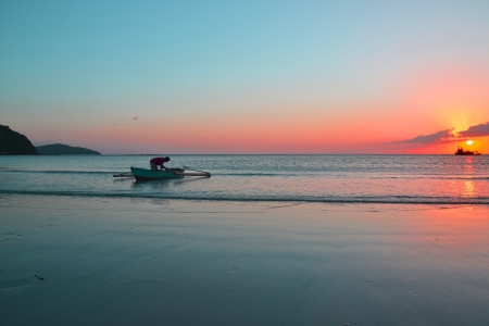 pink sunset with local people on a small canoeの写真素材