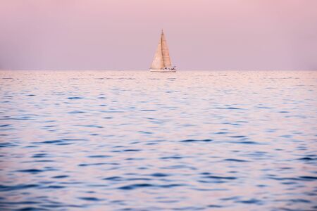 A romantic seascape with a sail boat after sunset, taken in Malta.の写真素材