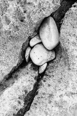 A detailed vertical black and white close up macro photograph of smooth rocks lying on the beach.の写真素材