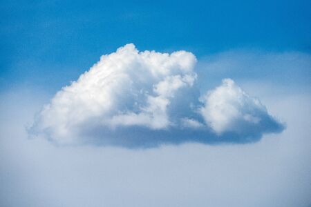 A close up photograph of a single white puffy cloud against a beautiful blue sky, taken in the Madikwe game Reserve, South Africa.の写真素材